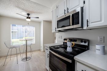 A kitchen with a stove and microwave and a table with a chair